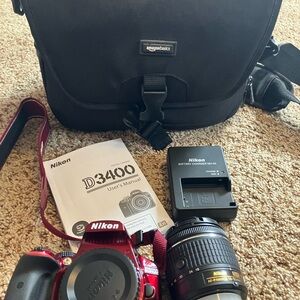 Nikon Red and Black Camera with accessories and Amazon basics bag